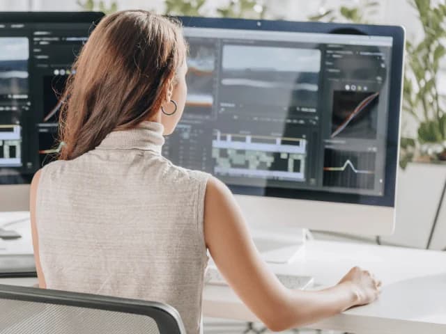 A woman at a desktop monitor with video editing software open