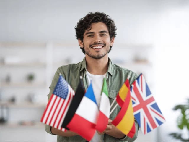 A smiling man holding small flags of the United States, France, Italy, Spain and the United Kingdom