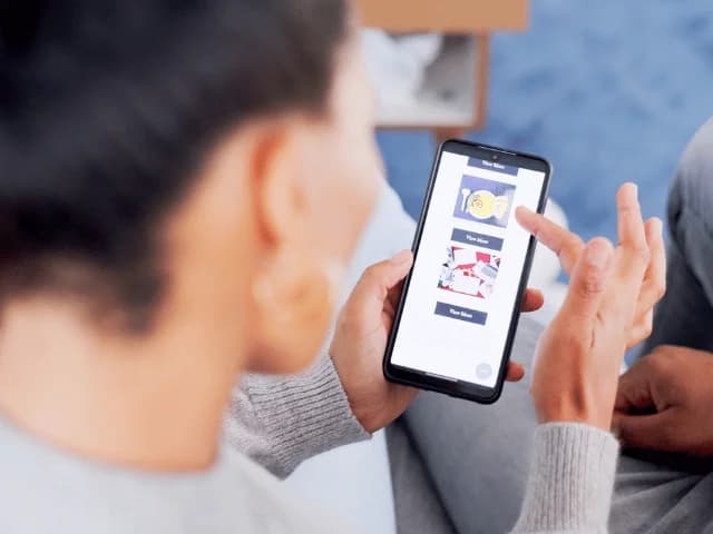 A person looking at a phone that shows an app menu with images